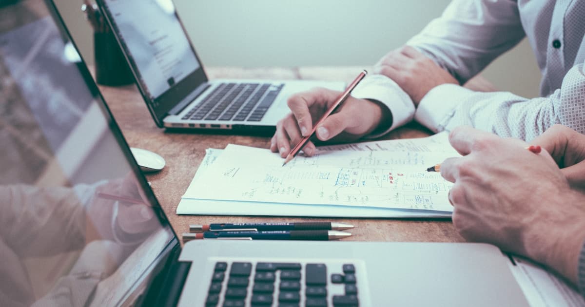 Business owner reviewing financial documents and laptop at a desk